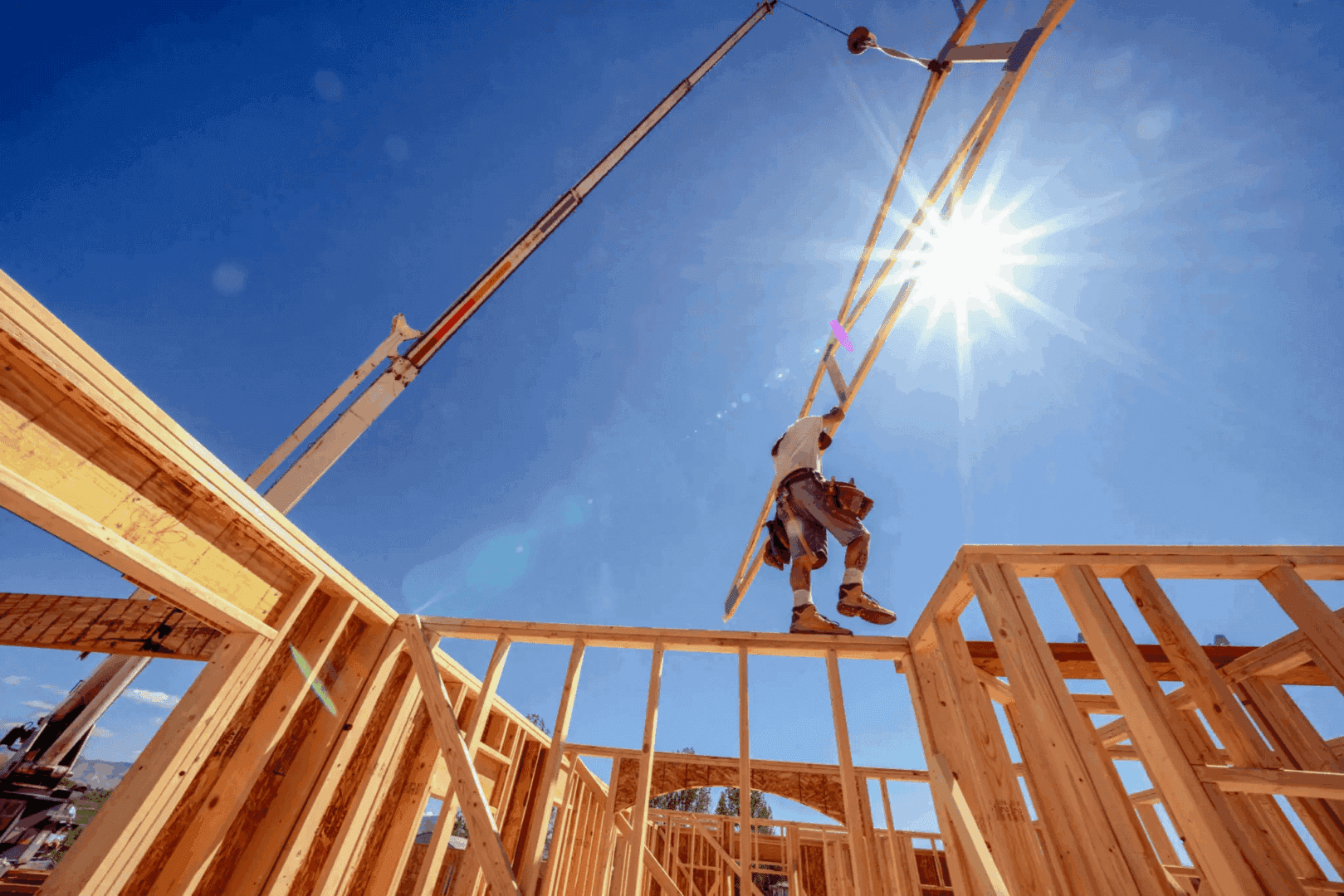 Construction worker balancing on wooden frame.