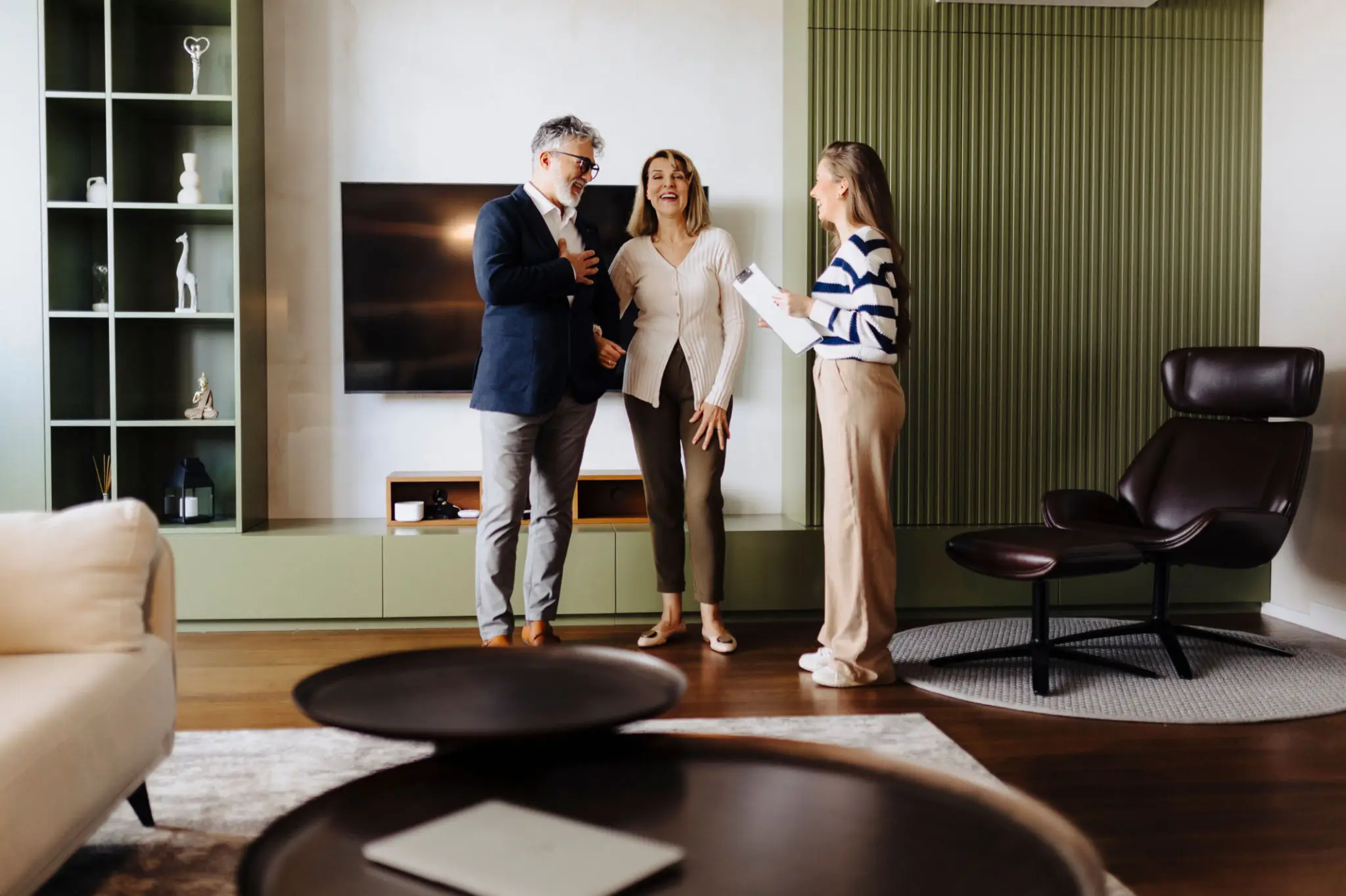 Couple talking to real estate agent indoors.