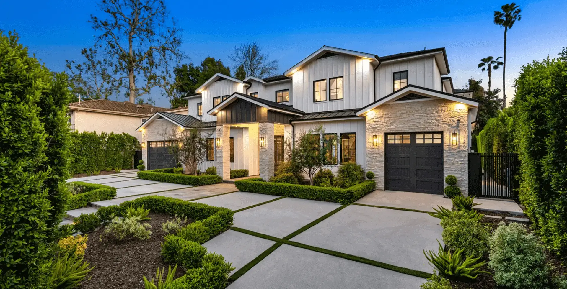 Modern house with landscaped front yard at dusk.