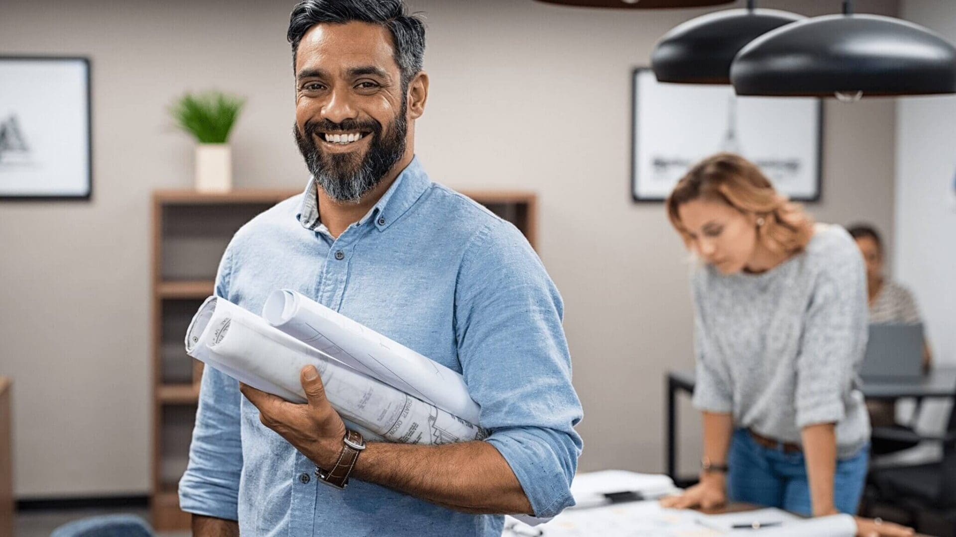 Smiling architect holding rolled blueprints.